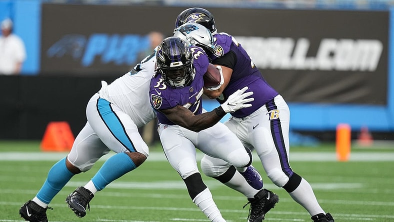 Aug 21, 2021; Charlotte, North Carolina, USA; Baltimore Ravens running back Gus Edwards (35) eludes a tackle by the Carolina Panthers defense for yardage during the first quarter at Bank of America Stadium. Mandatory Credit: Jim Dedmon-USA TODAY Sports