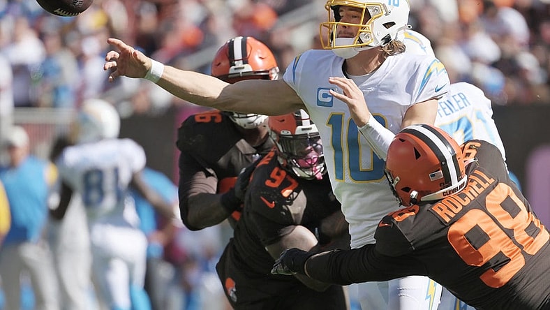 Oct 9, 2022; Cleveland, Ohio, USA; Los Angeles Chargers quarterback Justin Herbert (10) throws a pass as Cleveland Browns defensive end Isaac Rochell (98) and defensive tackle Perrion Winfrey (97) defend during the first half at FirstEnergy Stadium. Mandatory Credit: Ken Blaze-USA TODAY Sports
