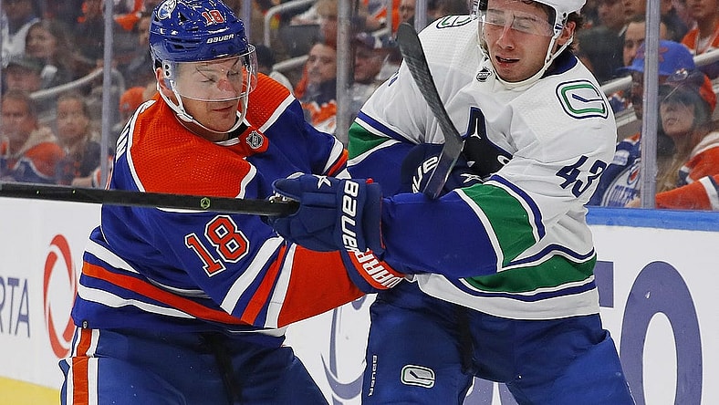 Oct 12, 2022; Edmonton, Alberta, CAN; Edmonton Oilers forward Zach Hyman (18) and Vancouver Canucks defensemen Quinn Hughes (43) battle for a loose puck during the first period at Rogers Place. Mandatory Credit: Perry Nelson-USA TODAY Sports