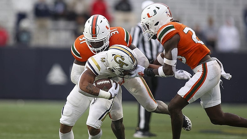 Nov 12, 2022; Atlanta, Georgia, USA; Georgia Tech Yellow Jackets running back Dontae Smith (4) has his face masked grabbed by Miami Hurricanes cornerback Te'Cory Couch (23) as linebacker Wesley Bissainthe (31) attempts to make a tackle in the second quarter at Bobby Dodd Stadium. Mandatory Credit: Brett Davis-USA TODAY Sports