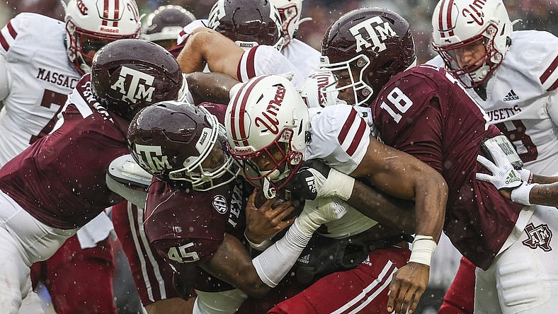 Nov 19, 2022; College Station, Texas, USA; Massachusetts Minutemen running back Ellis Merriweather (7) is tackled by Texas A&M Aggies linebacker Edgerrin Cooper (45) and defensive lineman LT Overton (18) during the first quarter at Kyle Field. Mandatory Credit: Troy Taormina-USA TODAY Sports