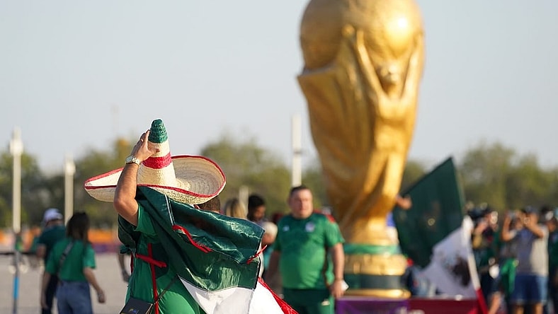 Nov 22, 2022; Doha, Qatar; A Mexico fan wearing a sombrero walks past a World Cup trophy replica outside the stadium before the match against Poland during a group stage match at the 2022 World Cup at Ras Abu Aboud Stadium. Mandatory Credit: Danielle Parhizkaran-USA TODAY Sports