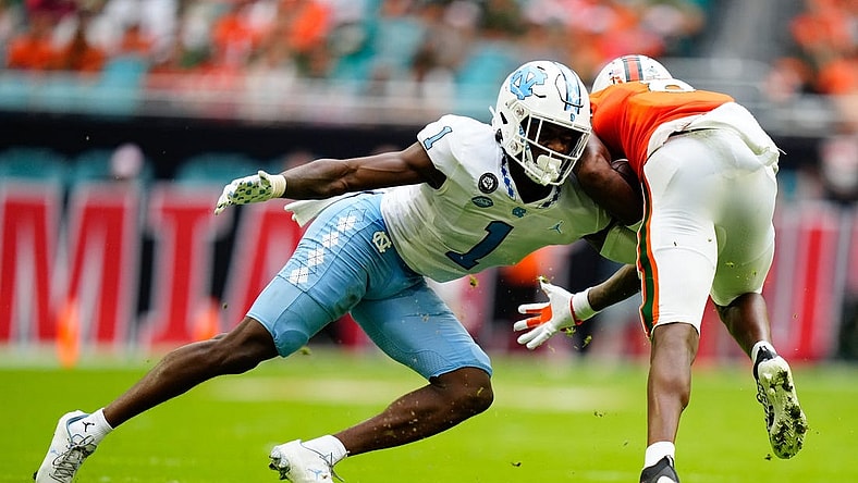 Oct 8, 2022; Miami Gardens, Florida, USA; North Carolina Tar Heels defensive back Tony Grimes (1) tackles Miami Hurricanes wide receiver Frank Ladson Jr. (8) during the first half at Hard Rock Stadium. Mandatory Credit: Rich Storry-USA TODAY Sports