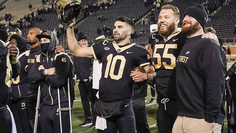 Nov 19, 2022; Winston-Salem, North Carolina, USA;  Wake Forest Demon Deacons quarterback Sam Hartman (10) holds up his helmet during the singing of the school alma mater after the win against the Syracuse Orange at Truist Field. Mandatory Credit: Jim Dedmon-USA TODAY Sports