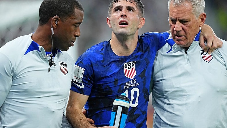 Nov 29, 2022; Doha, Qatar; United States of America forward Christian Pulisic (10) is helped after sustaining an injury after colliding with Iran goalkeeper Alireza Beiranvand (1) following his goal during the first half of a group stage match during the 2022 World Cup at Al Thumama Stadium. Mandatory Credit: Danielle Parhizkaran-USA TODAY Sports