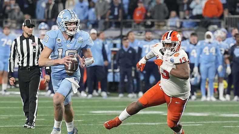 Dec 3, 2022; Charlotte, North Carolina, USA; North Carolina Tar Heels quarterback Drake Maye (10) scrambles past Clemson Tigers defensive tackle Tyler Davis (13) during the third quarter of the ACC Championship game at Bank of America Stadium.  Mandatory Credit: Jim Dedmon-USA TODAY Sports