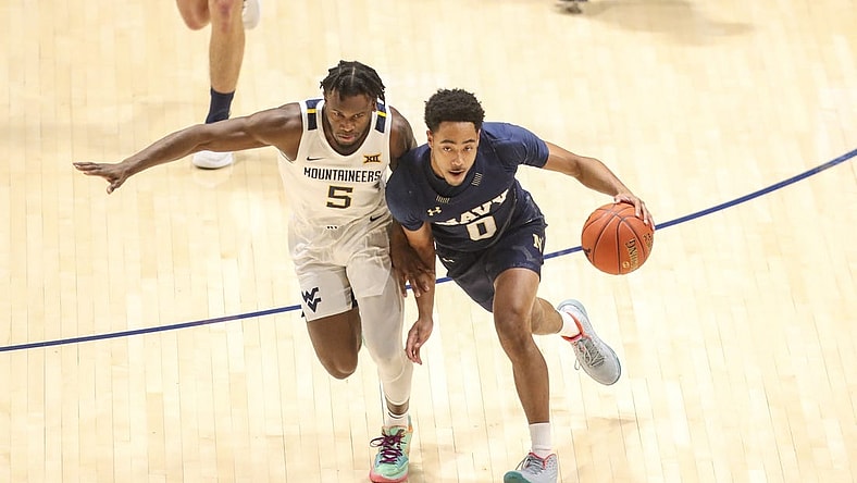 Dec 7, 2022; Morgantown, West Virginia, USA; Navy Midshipmen guard Austin Inge (0) dribbles against West Virginia Mountaineers guard Joe Toussaint (5) during the first half at WVU Coliseum. Mandatory Credit: Ben Queen-USA TODAY Sports