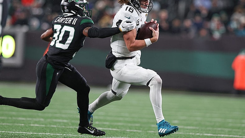 Dec 22, 2022; East Rutherford, New Jersey, USA; Jacksonville Jaguars quarterback Trevor Lawrence (16) carries the ball as New York Jets cornerback Michael Carter II (30) attempts to tackle during the first half at MetLife Stadium. Mandatory Credit: Vincent Carchietta-USA TODAY Sports