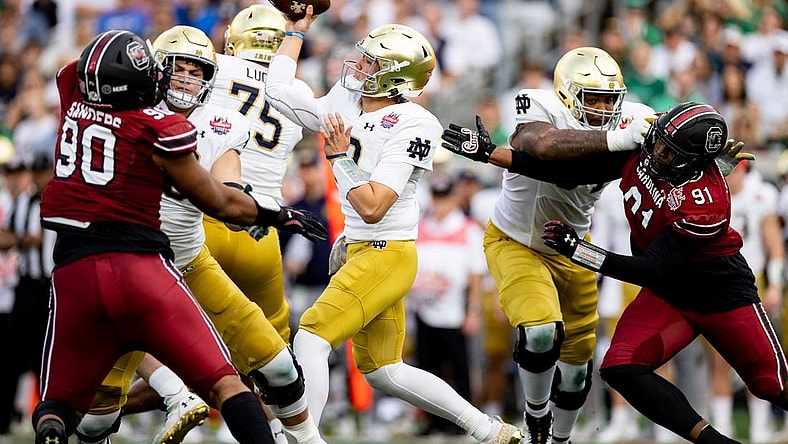 Dec 30, 2022; Jacksonville, FL, USA; Notre Dame Fighting Irish quarterback Tyler Buchner (12) throws the ball under pressure from South Carolina Gamecocks defensive lineman Tonka Hemingway (91) and defensive lineman T.J. Sanders (90) during the first half in the 2022 Gator Bowl at TIAA Bank Field. Mandatory Credit: Matt Pendleton-USA TODAY Sports