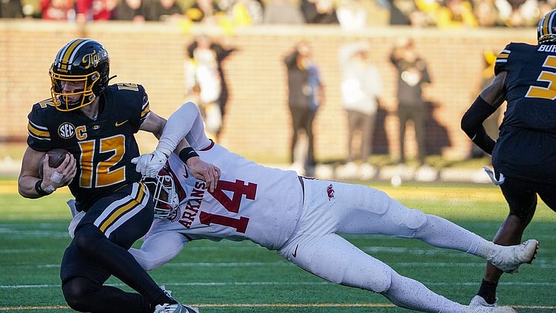 Nov 25, 2022; Columbia, Missouri, USA; Missouri Tigers quarterback Brady Cook (12) is tackled by Arkansas Razorbacks defensive lineman Jordan Domineck (14) during the first half at Faurot Field at Memorial Stadium. Mandatory Credit: Denny Medley-USA TODAY Sports