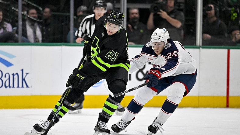 Feb 18, 2023; Dallas, Texas, USA; Dallas Stars left wing Jason Robertson (21) keeps the puck away from Columbus Blue Jackets right wing Mathieu Olivier (24) during the first period at the American Airlines Center. Mandatory Credit: Jerome Miron-USA TODAY Sports