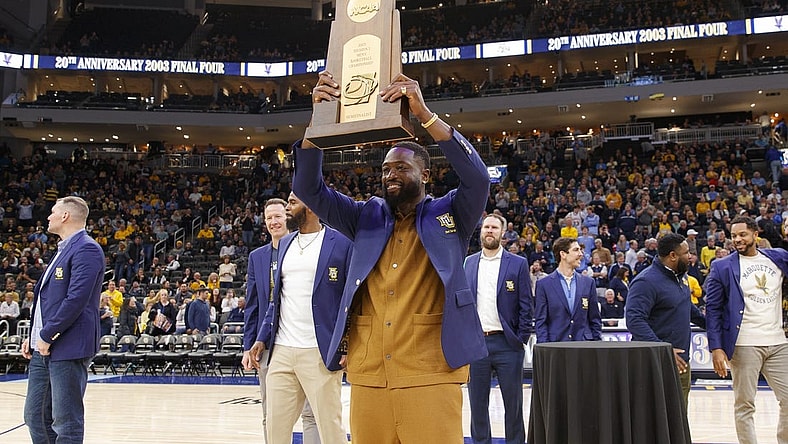 Jan 18, 2023; Milwaukee, Wisconsin, USA;  Former Marquette Golden Eagles player Dwayne Wade holds up the 2003 Division One Semifinalist trophy during a ceremony honoring the 20th anniversary of reaching the Final Four during halftime of the game between the Providence Friars and Marquette Golden Eagles at Fiserv Forum. Mandatory Credit: Jeff Hanisch-USA TODAY Sports