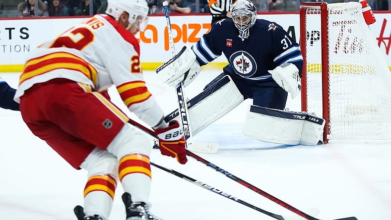 Apr 5, 2023; Winnipeg, Manitoba, CAN;  Winnipeg Jets goalie Connor Hellebuyck (37) watches Calgary Flames forward Trevor Lewis (22) during the first period at Canada Life Centre. Mandatory Credit: Terrence Lee-USA TODAY Sports