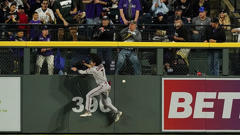 Apr 29, 2023; Denver, Colorado, USA;  Arizona Diamondbacks left fielder Corbin Carroll (7) falls after banging into the outfield wall at Coors Field.  Carroll left the game after the play. Mandatory Credit: Michael Madrid-USA TODAY Sports