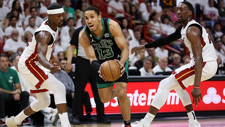 May 21, 2023; Miami, Florida, USA; Boston Celtics guard Malcolm Brogdon (13) drives against Miami Heat forward Jimmy Butler (22) and center Bam Adebayo (13) during the third quarter in game three of the Eastern Conference Finals for the 2023 NBA playoffs at Kaseya Center. Mandatory Credit: Sam Navarro-USA TODAY Sports