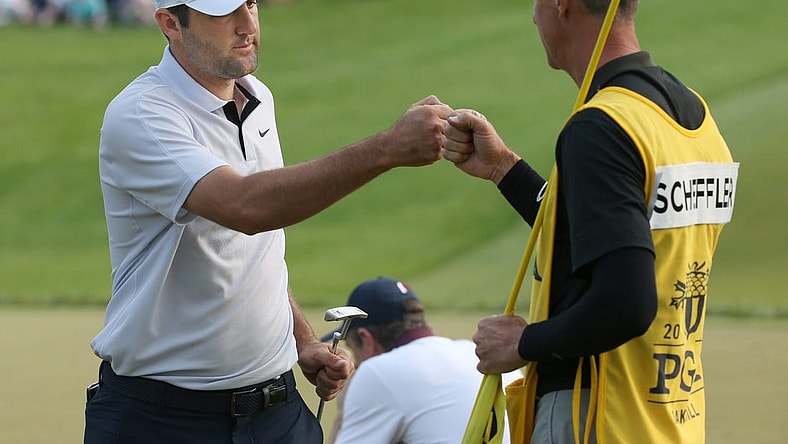 Scottie Scheffler fist-bumps his caddie Ted Scott after his final putt at the 18th hole during the final round at the PGA Championship at Oak Hill Country Club Sunday, May 21, 2023.