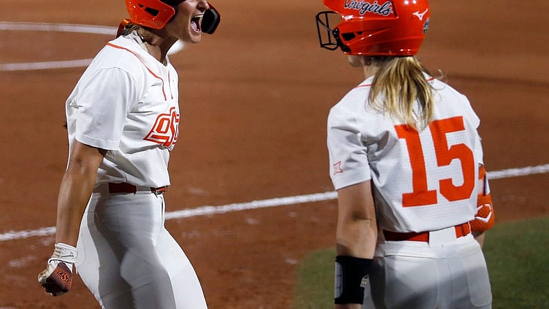 Oklahoma State's Kiley Naomi (5) celebrates a score with Rachel Becker (15) in the first inning during a softball game between Oklahoma State and Utah in the Women's College World Series at USA Softball Hall of Fame Stadium in  in Oklahoma City, Friday, June, 2, 2023.