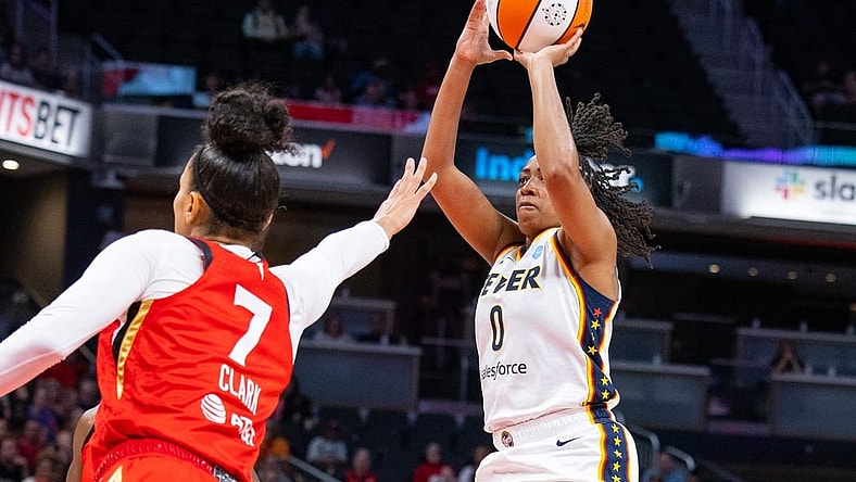 Jun 4, 2023; Indianapolis, Indiana, USA; Indiana Fever guard Kelsey Mitchell (0) shoots the ball while Las Vegas Aces forward Alysha Clark (7) defends in the first half at Gainbridge Fieldhouse. Mandatory Credit: Trevor Ruszkowski-USA TODAY Sports