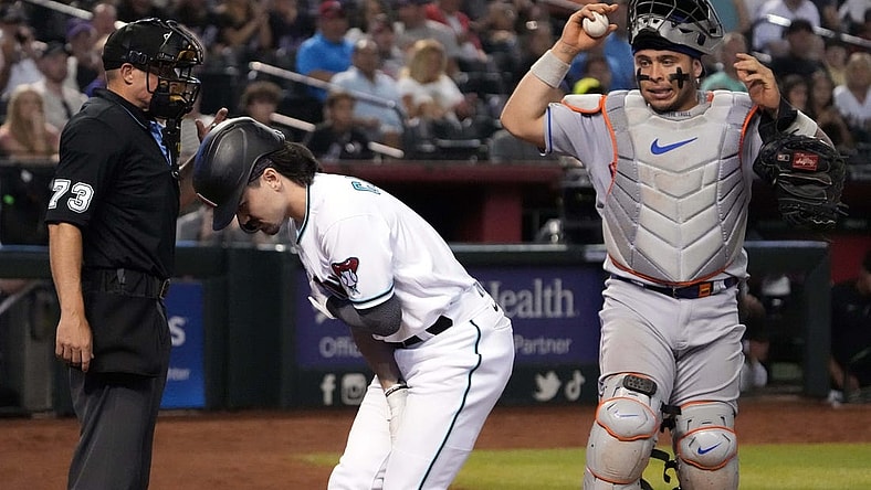 Jul 6, 2023; Phoenix, Arizona, USA; Home plate umpire Tripp Gibson (73) and New York Mets catcher Francisco Alvarez (4) watch as Arizona Diamondbacks left fielder Corbin Carroll (7) tends to an injury during the seventh inning at Chase Field. Mandatory Credit: Joe Camporeale-USA TODAY Sports