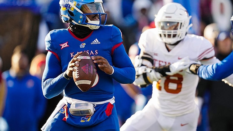 Nov 19, 2022; Lawrence, Kansas, USA; Kansas Jayhawks quarterback Jalon Daniels (6) drops back to pass as Texas Longhorns defensive end Ovie Oghoufo (18) defends during the first half at David Booth Kansas Memorial Stadium. Mandatory Credit: Jay Biggerstaff-USA TODAY Sports