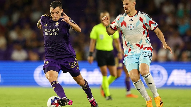 Jul 1, 2023; Orlando, Florida, USA;  Orlando City SC defender Kyle Smith (24) controls the ball from Chicago Fire FC midfielder Gaston Gimenez (30) in the second half at Exploria Stadium. Mandatory Credit: Nathan Ray Seebeck-USA TODAY Sports