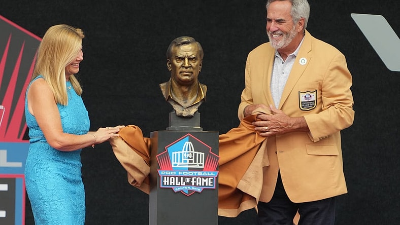 Aug 5, 2023; Canton, OH, USA;   Dan Fouts and Mindy Coryell Lewis unveil the bust of San Diego Chargers and St. Louis Cardinals former coach Don Coryell (deceased) during the 2023 Pro Football Hall of Fame Enshrinement at Tom Benson Hall of Fame Stadium. Mandatory Credit: Kirby Lee-USA TODAY Sports