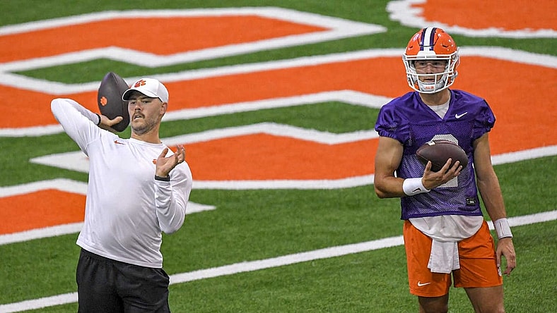 Clemson offensive coordinator Garrett Riley passes a ball while quarterback Cade Klubnik (2) watches during preseason practice at the Poe Indoor Practice Facility at the Allen N. Reeves football complex in Clemson, S.C. Monday, August 7, 2023.