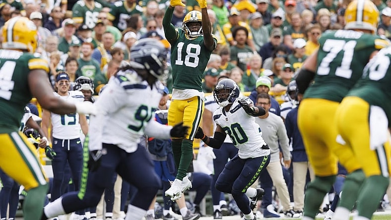 Aug 26, 2023; Green Bay, Wisconsin, USA;  Green Bay Packers wide receiver Malik Heath (18) leaps to catch a pass in front of Seattle Seahawks cornerback Michael Jackson (30) during the first quarter at Lambeau Field. Mandatory Credit: Jeff Hanisch-USA TODAY Sports