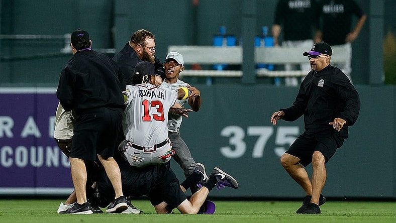 Aug 28, 2023; Denver, Colorado, USA; A fan charges at Atlanta Braves right fielder Ronald Acuna Jr. (13) as grounds crew detains another person in the seventh inning against the Colorado Rockies at Coors Field. Mandatory Credit: Isaiah J. Downing-USA TODAY Sports