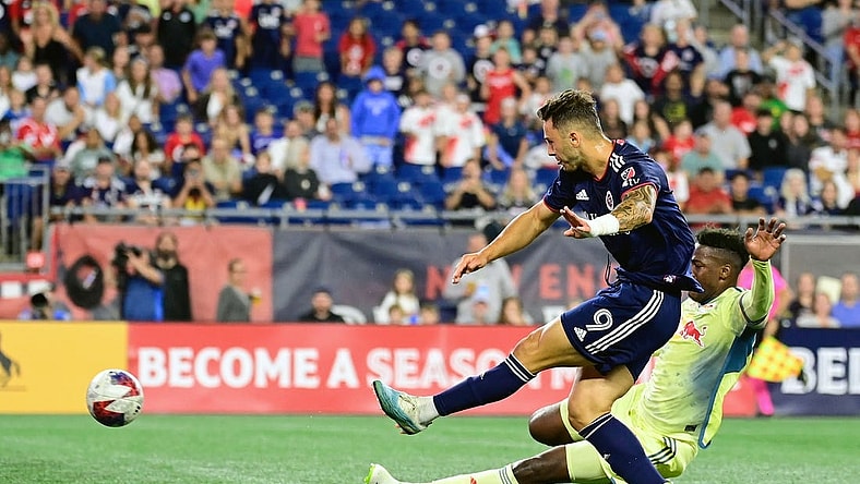 Aug 30, 2023; Foxborough, Massachusetts, USA; New England Revolution attacker Giacomo Vrioni (9) scores a goal as New York Red Bulls defender Hassan Ndam (98) slides to defend the shot during the first half at Gillette Stadium. Mandatory Credit: Eric Canha-USA TODAY Sports