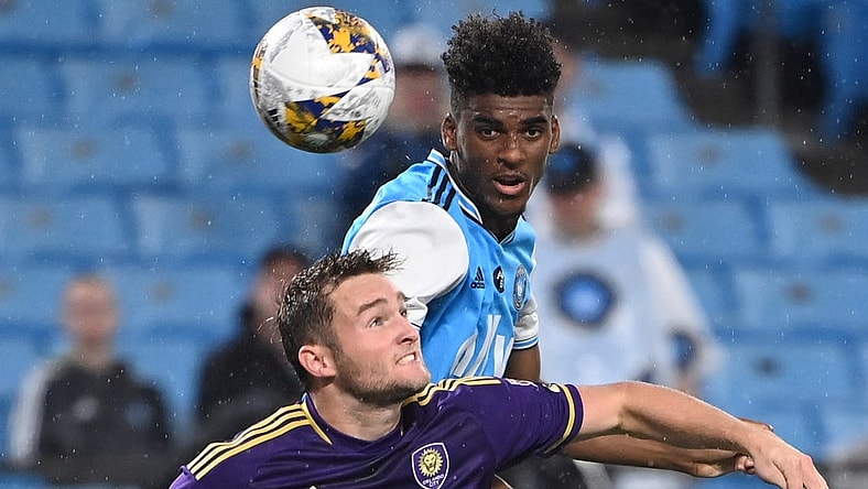 Aug 30, 2023; Charlotte, North Carolina, USA; Charlotte FC defender Adilson Malanda (29) heads the ball as Orlando City forward Duncan McGuire (13) defends in the first half at Bank of America Stadium. Mandatory Credit: Bob Donnan-USA TODAY Sports