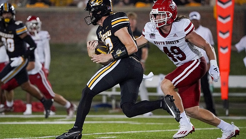 Aug 31, 2023; Columbia, Missouri, USA; Missouri Tigers quarterback Brady Cook (12) runs the ball as South Dakota Coyotes linebacker Brock Mogensen (49) defends during the first half at Faurot Field at Memorial Stadium. Mandatory Credit: Denny Medley-USA TODAY Sports