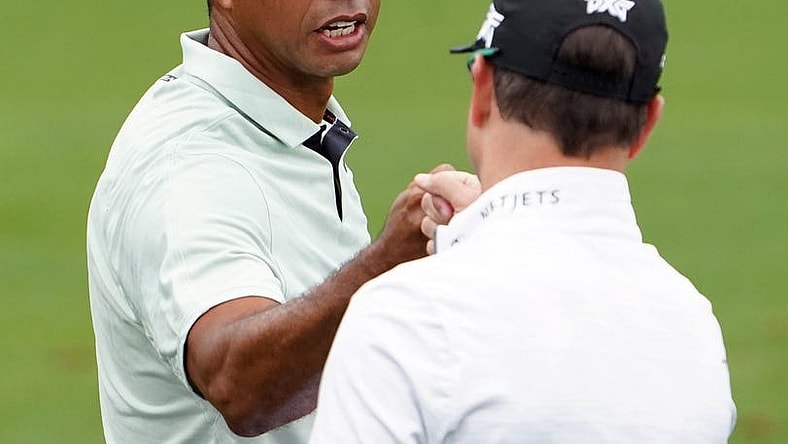 Apr 5, 2022; Augusta, Georgia, USA; Tiger Woods gives Zach Johnson a fist bump on the practice range during a practice round of The Masters golf tournament at Augusta National Golf Club. Mandatory Credit: Danielle Parhizkaran-Augusta Chronicle/USA TODAY Network