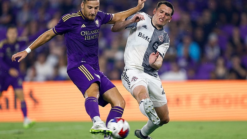 Jul 4, 2023; Orlando, Florida, USA; Orlando City forward Ercan Kara (9) shoots and scores as Toronto FC defender Shane O'Neill (27) defends during the second half at Exploria Stadium. Mandatory Credit: Douglas DeFelice-USA TODAY Sports