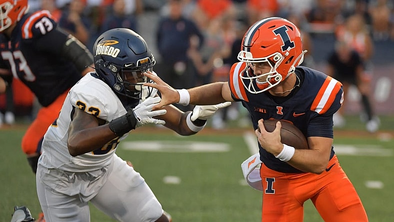 Sep 2, 2023; Champaign, Illinois, USA;  Illinois Fighting Illini quarterback Luke Altmyer (9) puts a hand to the helmet of Toledo Rockets linebacker CJ Wilson Jr. (33) on a run during the first half at Memorial Stadium. Mandatory Credit: Ron Johnson-USA TODAY Sports