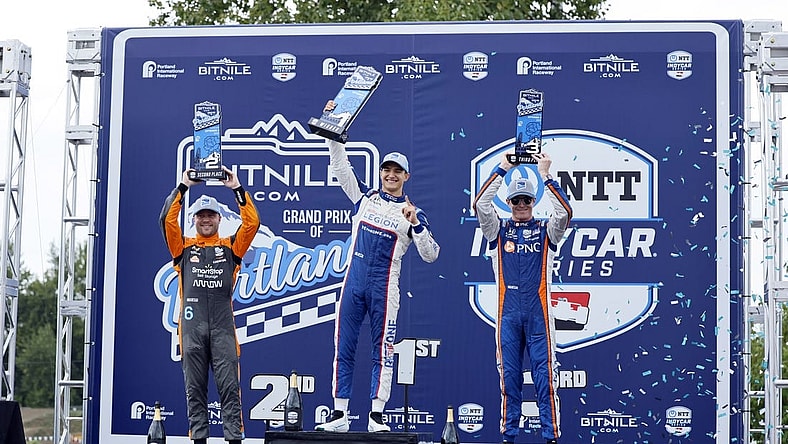 Sep 3, 2023; Portland, Oregon, USA; NTT Indy Car driver Alex Palou (center) lifts his first place trophy with second place finisher Felix Rosenqvist (left) and third place finisher Scott Dixon (right) at Portland International Raceway. Mandatory Credit: Soobum Im-USA TODAY Sports