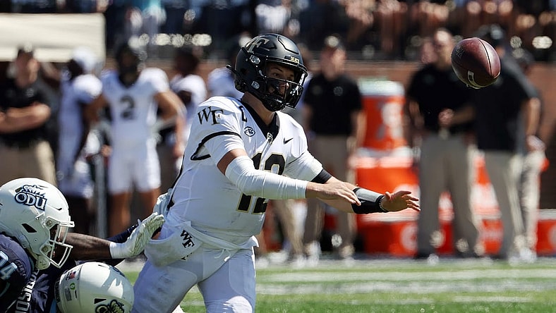 Sep 16, 2023; Norfolk, Virginia, USA; Wake Forest Demon Deacons quarterback Mitch Griffis (12) fumbles the ball while being tackled by Old Dominion Monarchs defensive end Amorie Morrison (4) and linebacker EJ Green (24) during the second quarter at Kornblau Field at S.B. Ballard Stadium. Mandatory Credit: Peter Casey-USA TODAY Sports