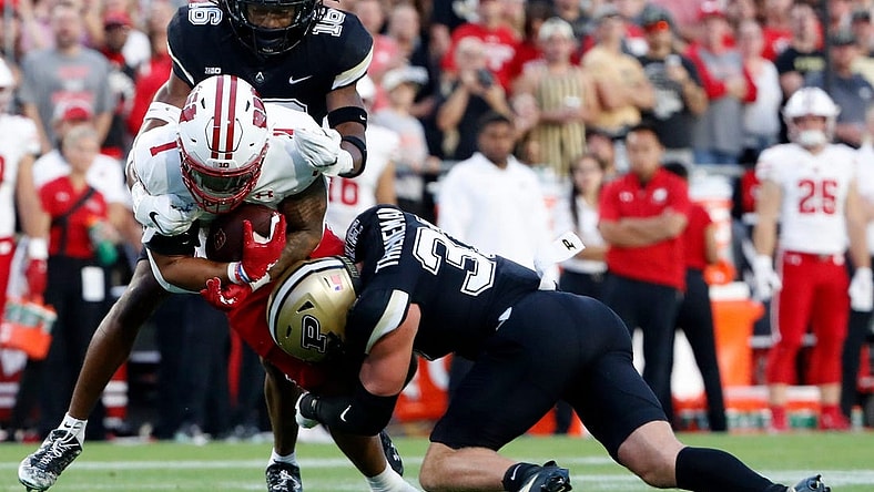 Wisconsin Badgers running back Chez Mellusi (1) is tackled by Purdue Boilermakers defensive back Marquis Wilson (16) and Purdue Boilermakers defensive back Dillon Thieneman (31) during the NCAA football game, Friday, Sept. 22, 2023, at Ross-Ade Stadium in West Lafayette, Ind.
