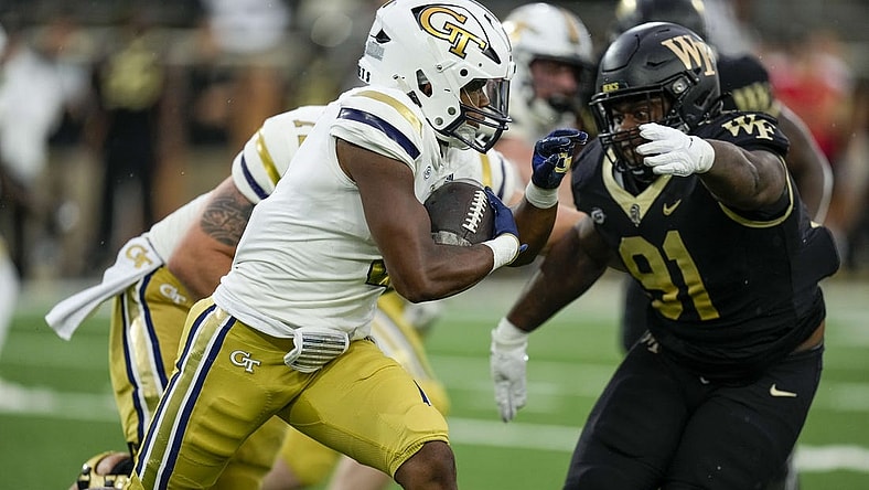 Sep 23, 2023; Winston-Salem, North Carolina, USA;  Georgia Tech Yellow Jackets running back Trey Cooley (0) runs the ball against Wake Forest Demon Deacons defensive lineman Kevin Pointer (91) during the first half at Allegacy Federal Credit Union Stadium. Mandatory Credit: Jim Dedmon-USA TODAY Sports