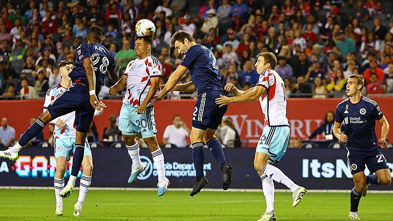 Sep 23, 2023; Chicago, Illinois, USA; Chicago Fire midfielder Jairo Torres (20) heads the ball against New England Revolution defender Dave Romney (2) during the first half at Soldier Field. Mandatory Credit: Mike Dinovo-USA TODAY Sports