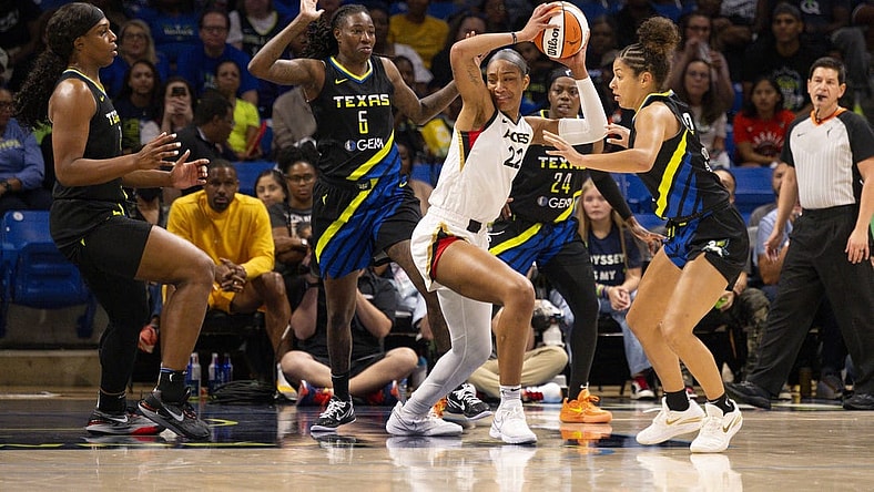 Sep 29, 2023; Arlington, Texas, USA; Las Vegas Aces forward A'ja Wilson (22) looks to move the ball past Dallas Wings forward Natasha Howard (6) and guard Arike Ogunbowale (24) and center Teaira McCowan (7) during the first half during game three of the 2023 WNBA Playoffs at College Park Center. Mandatory Credit: Jerome Miron-USA TODAY Sports
