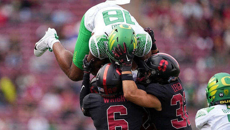 Sep 30, 2023; Stanford, California, USA; Oregon Ducks tight end Kenyon Sadiq (18) attempts to leap over Stanford Cardinal cornerback Collin Wright (6) and safety Mitch Leigber (32) during the second quarter at Stanford Stadium. Mandatory Credit: Darren Yamashita-USA TODAY Sports