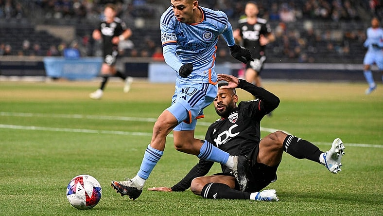 Mar 18, 2023; New York, New York, USA; New York City FC midfielder Santiago Rodriguez (10) jumps over a sliding D.C. United defender Ruan (2) during the first half at Yankee Stadium. Mandatory Credit: Mark Smith-USA TODAY Sports