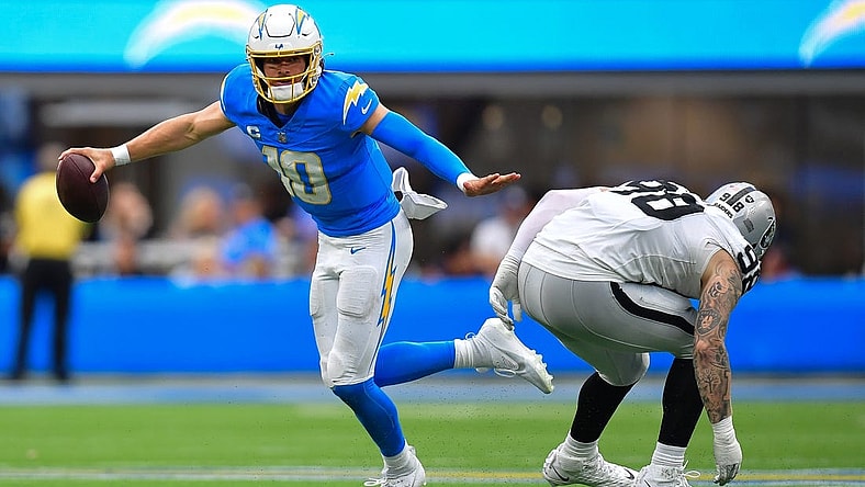 Oct 1, 2023; Inglewood, California, USA; Los Angeles Chargers quarterback Justin Herbert (10) moves the ball against Las Vegas Raiders defensive end Maxx Crosby (98) during the first half at SoFi Stadium. Mandatory Credit: Gary A. Vasquez-USA TODAY Sports