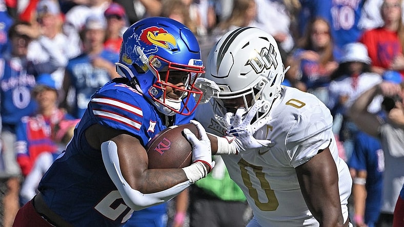 Oct 7, 2023; Lawrence, Kansas, USA;  Kansas Jayhawks running back Daniel Hishaw Jr. (20) runs up field against UCF Knights linebacker Jason Johnson (0) during the first half at David Booth Kansas Memorial Stadium. Mandatory Credit: Peter Aiken-USA TODAY Sports