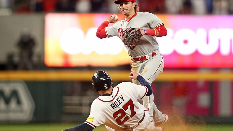 Oct 7, 2023; Cumberland, Georgia, USA; Philadelphia Phillies second baseman Bryson Stott (5) turns a double play over Atlanta Braves third baseman Austin Riley (27) during the eighth inning during game one of the NLDS for the 2023 MLB playoffs at Truist Park. Mandatory Credit: Brett Davis-USA TODAY Sports