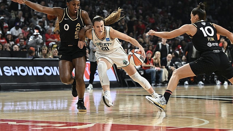 Oct 8, 2023; Las Vegas, Nevada, USA; New York Liberty guard Sabrina Ionescu (20) drives past Las Vegas Aces guard Jackie Young (0) and guard Kelsey Plum (10) in the first half during game one of the 2023 WNBA Finals at Michelob Ultra Arena. Mandatory Credit: Candice Ward-USA TODAY Sports