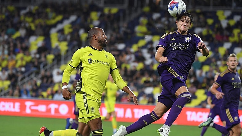 Oct 4, 2023; Nashville, Tennessee, USA; Orlando City defender Rodrigo Schlegel (15) heads the ball against Nashville SC forward Teal Bunbury (12) during the second half at Geodis Park. Mandatory Credit: Christopher Hanewinckel-USA TODAY Sports