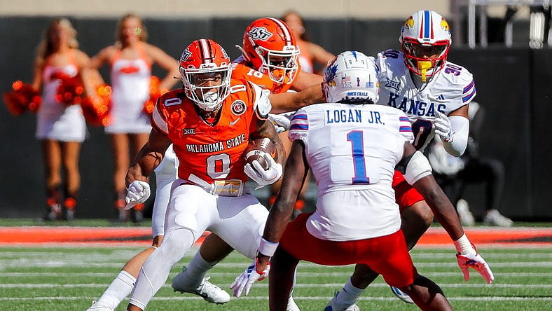 Oct 14, 2023; Stillwater, Oklahoma, USA; Oklahoma State's Ollie Gordon II (0) runs the ball against Kansas Jayhawks s Kenny Logan Jr. (1) in the first quarter at Boone Pickens Stadium. Mandatory Credit: Nathan J. Fish-USA TODAY Sports