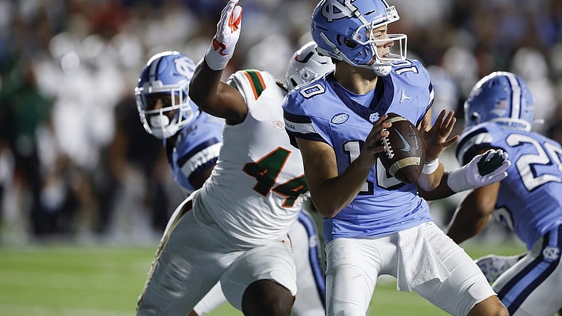 Oct 14, 2023; Chapel Hill, North Carolina, USA; North Carolina Tar Heels quarterback Drake Maye (10) looks to pass as he is chased by Miami Hurricanes defensive lineman Rueben Bain Jr. (44) in the first half at Kenan Memorial Stadium. Mandatory Credit: Nell Redmond-USA TODAY Sports